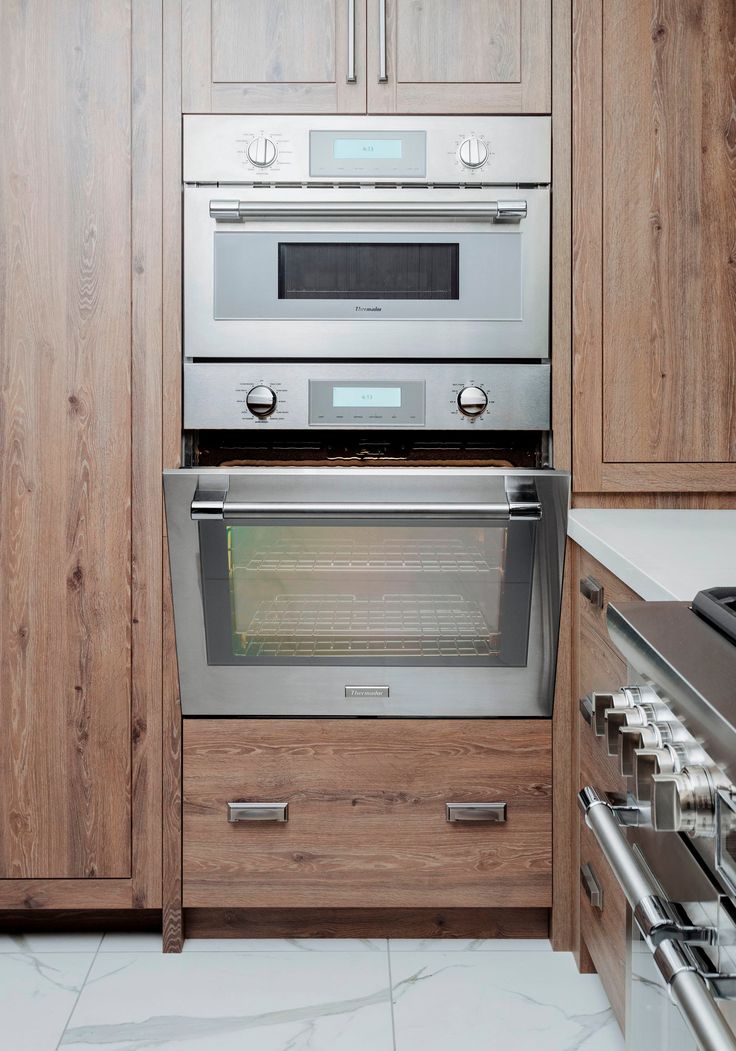 a stainless steel oven and stove in a kitchen with wooden cabinets on the wall behind it