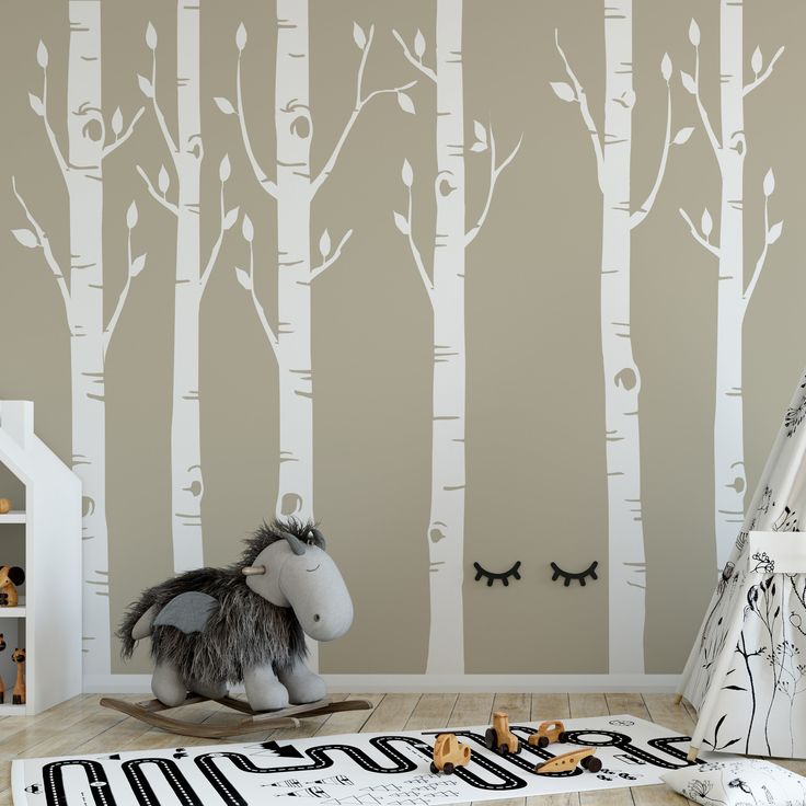 a child's room decorated in blue and white with birch trees on the wall