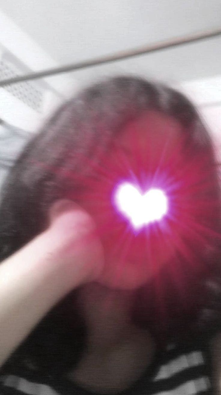 a woman holding her hand up to her face with a heart shaped light in the middle