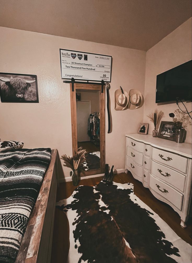 a bedroom with a cow hide rug on the floor next to a dresser and mirror