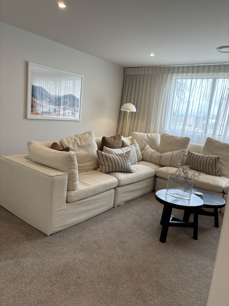 a living room filled with furniture next to a window covered in sheer curtained drapes