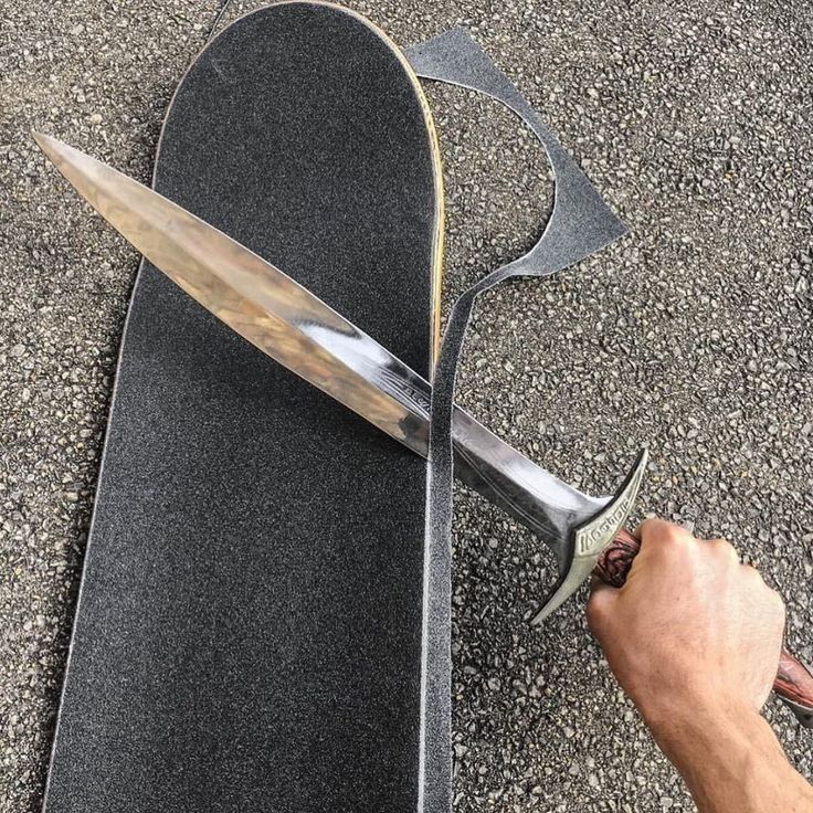 a person is holding a large knife on top of a skateboard