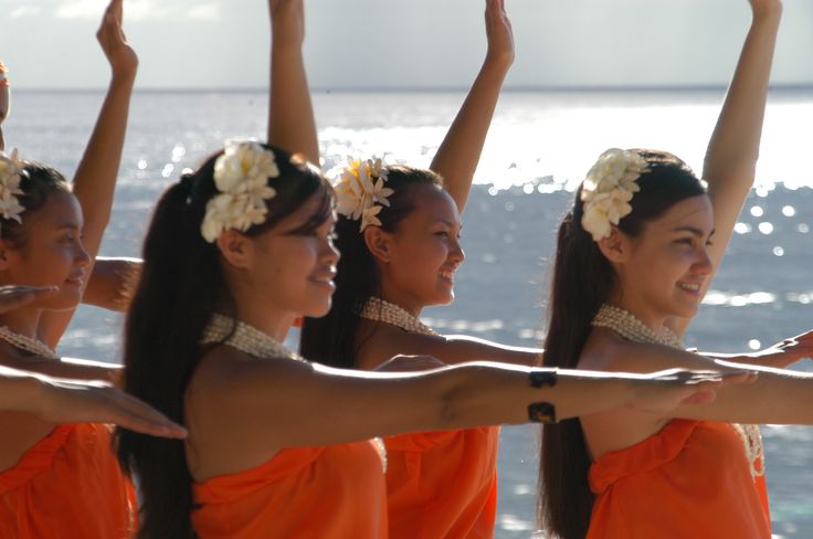 four women in orange dresses are holding their hands up