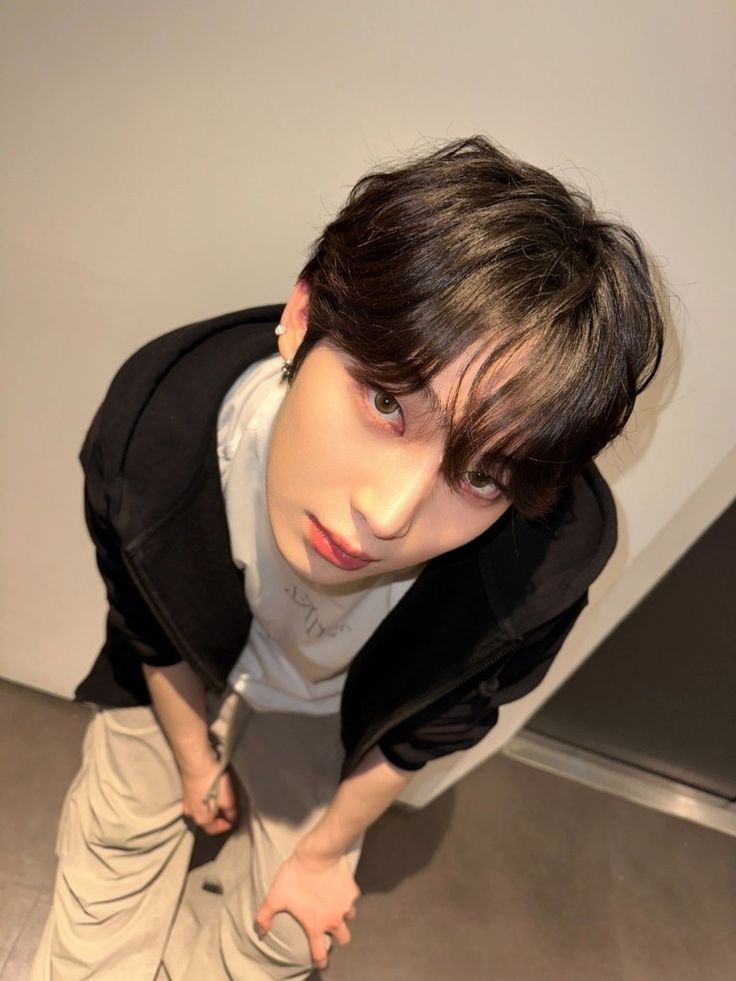 a young man standing in front of a white wall