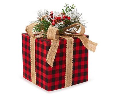 a red and black checkered christmas present box with pine branches, berries and mist