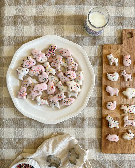 a table topped with lots of cookies and sprinkles next to a glass of milk