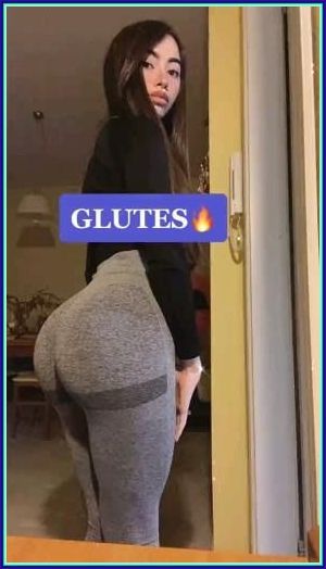 a woman standing in front of a door wearing leggings with the words glutes on it