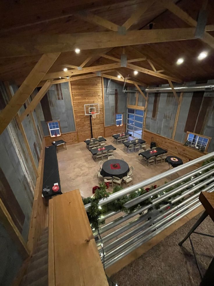 an indoor basketball court with tables, chairs and lights on the ceiling is lit up at night