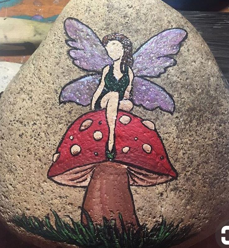 a painted rock with a fairy sitting on top of it