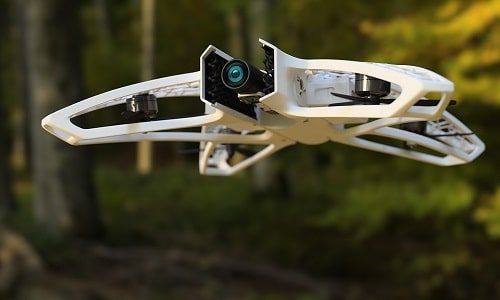 a close up of a camera attached to a white object in the air with trees in the background