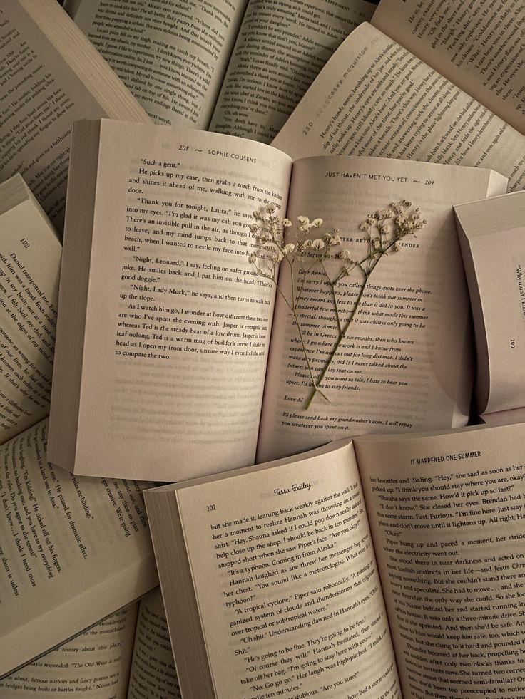 an open book with a flower on top of it in front of many pages that are stacked together