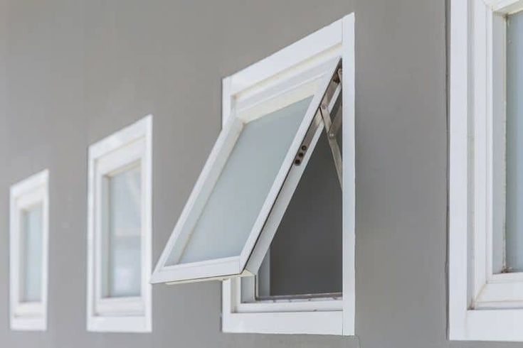 three windows with white trim on the side of a wall and one has a window pane