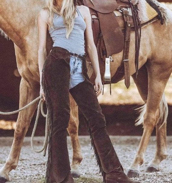 This Exquisite Leather & Suede Chaps Features a Striking Fringes & Non Fringes Style emblem, making it a perfect accessory for western wear, Cowgirl wear Equestrian ensembles. Crafted entirely by hand Made, this unique piece combines durability with style, ensuring it stands out at any occasion. Embrace your individuality with this versatile and eye-catching hat that seamlessly blends classic elegance with a rebellious Chap Chap Has Difference Sizes of Waist ,Inseam and Thigh if the Customer wan Cowgirl Chaps, Wild West Costumes, Cowboy Chaps, Western Chaps, Cowgirl Halloween, Chapped Hands, Riding Chaps, Fringe Pants, Cowboy Costume