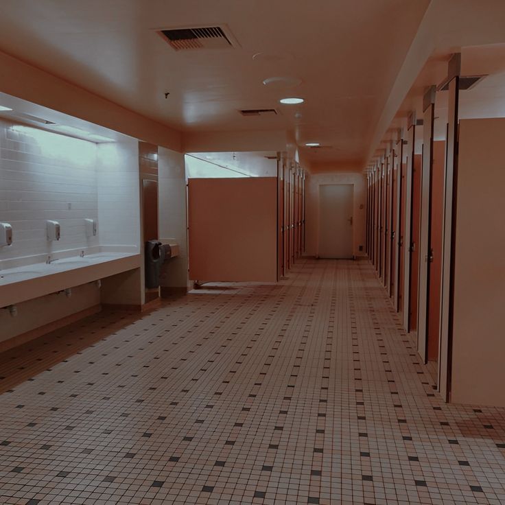 an empty public restroom with stalls and sinks