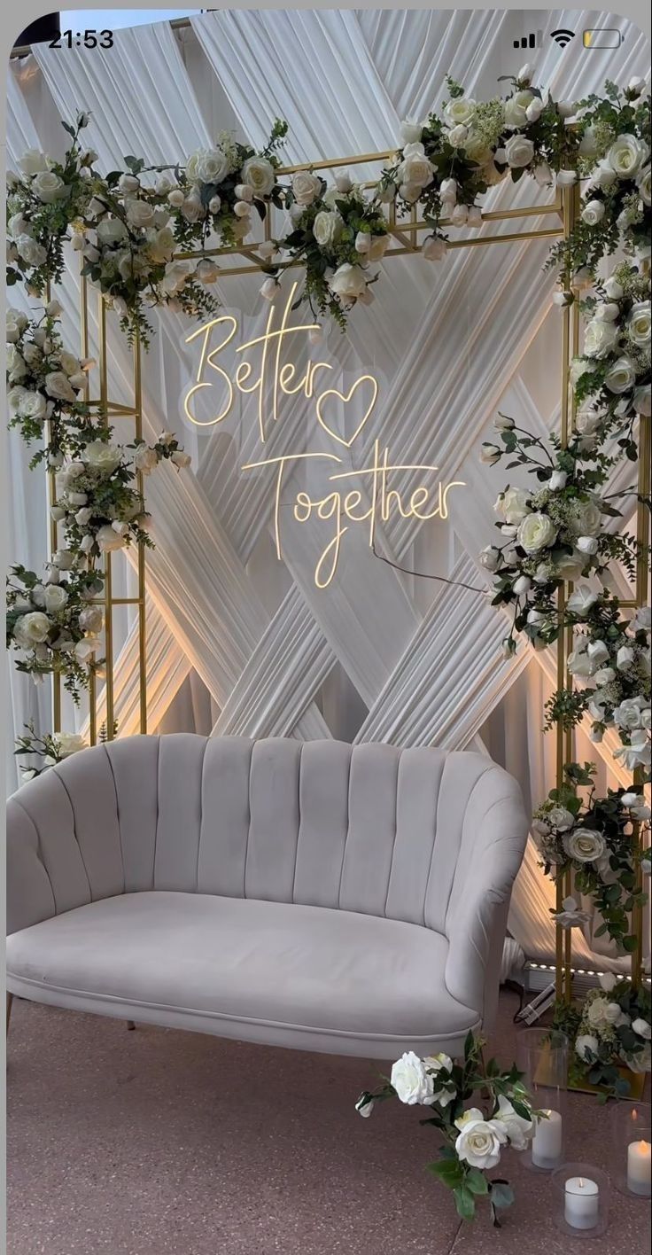 a white couch sitting under a sign that says better together next to flowers and candles