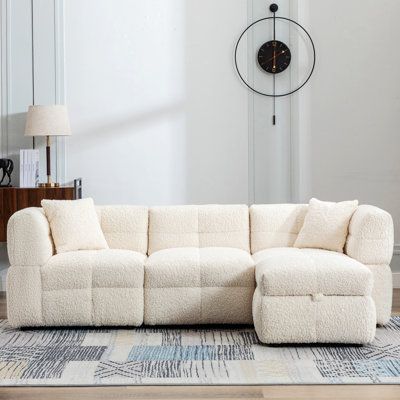 a living room with a sectional couch and large clock on the wall in the background