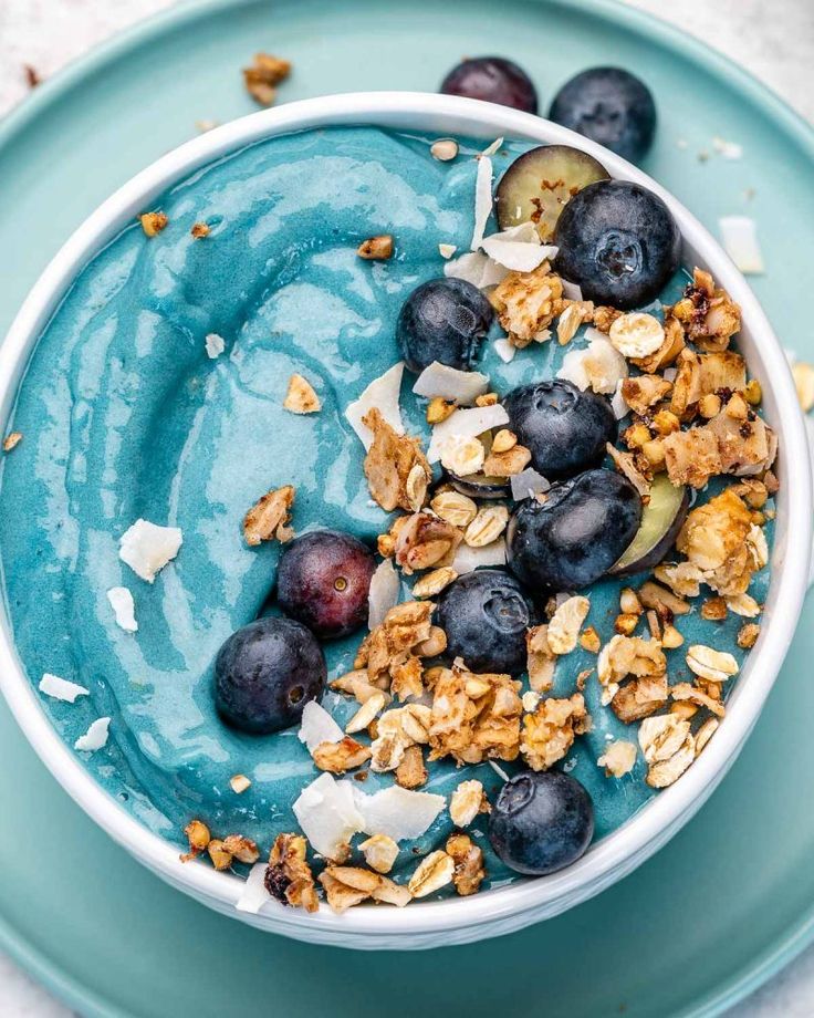 a bowl filled with yogurt and blueberries on top of a green plate