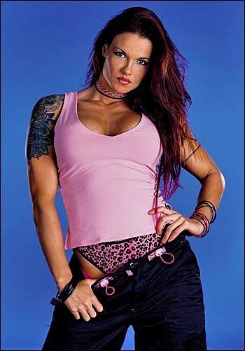 a woman in pink shirt and black pants with tattoos on her arm, posing for the camera