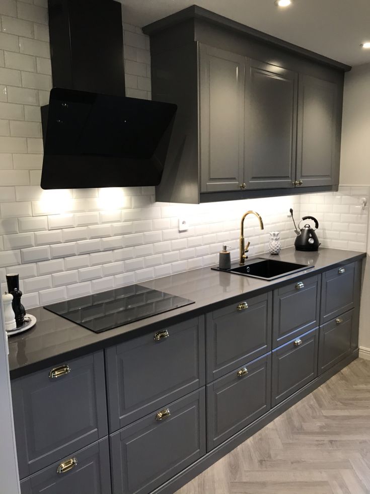 a kitchen with gray cabinets and black appliances