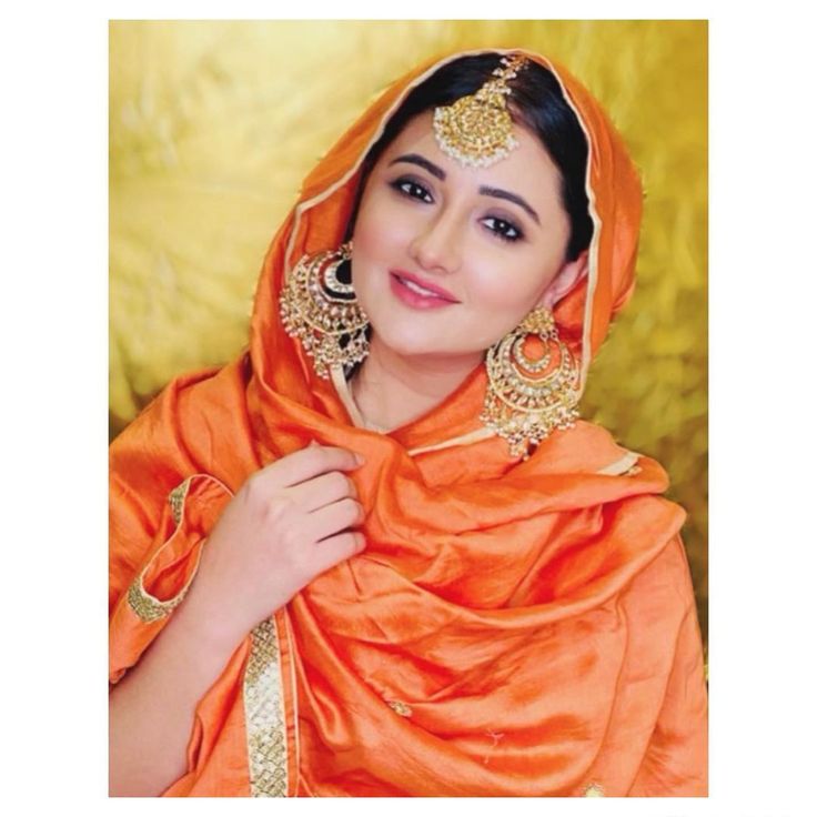 a woman wearing an orange outfit and gold jewelry