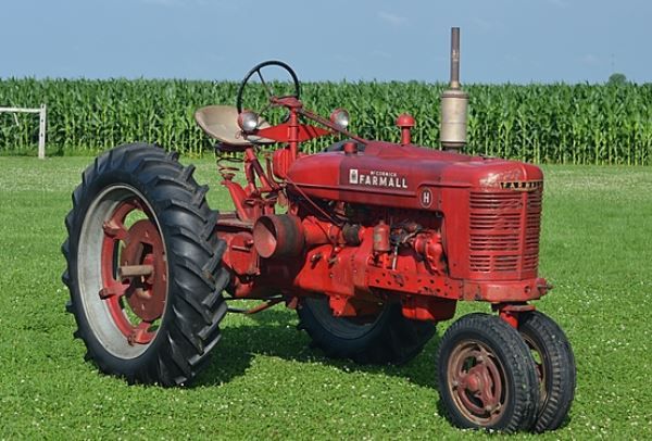 an old red tractor sitting in the middle of a field