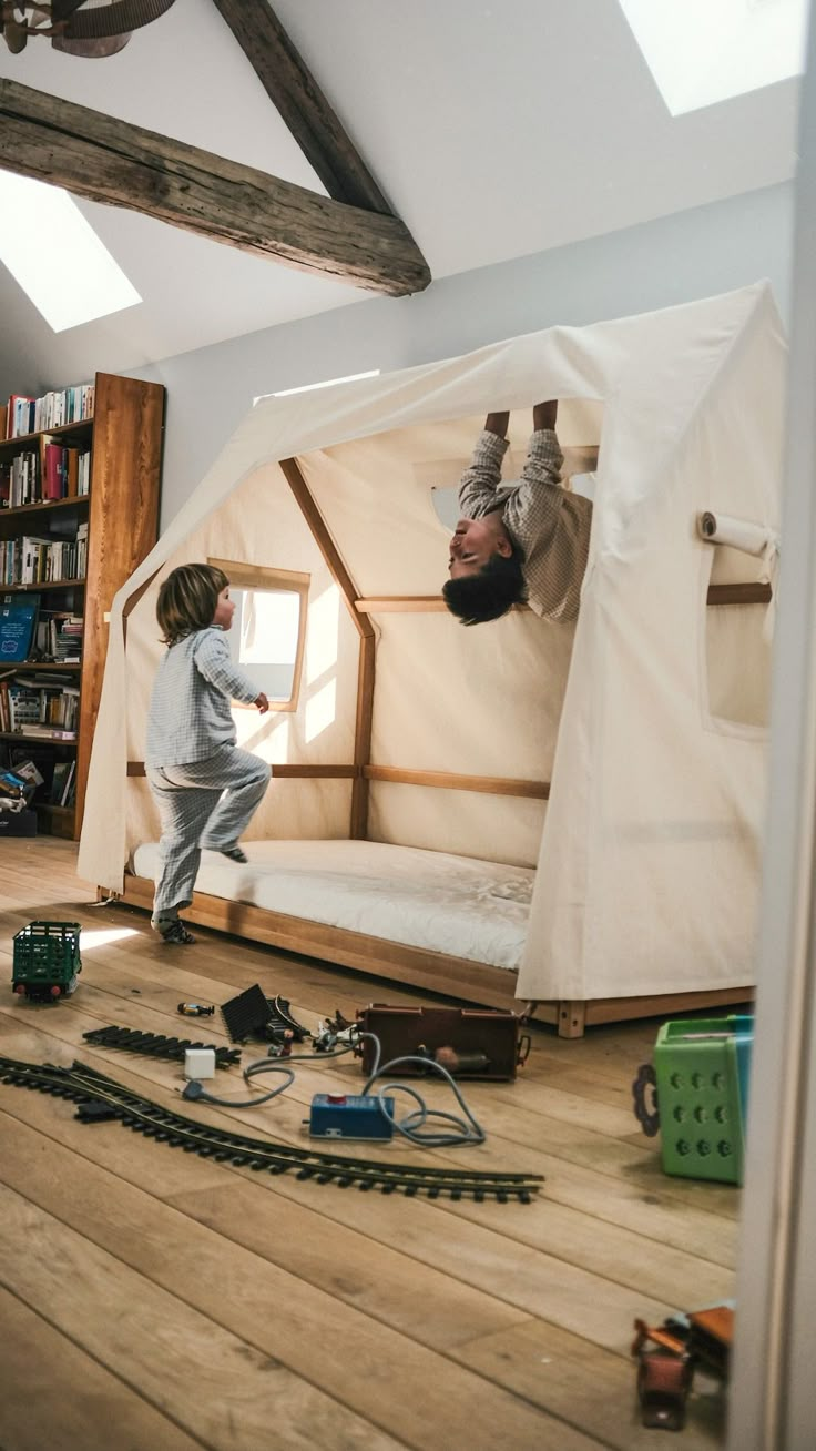 a child is playing on the floor next to a bed in a room with wooden floors