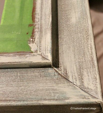 an old wooden bench with green grass in the backround and peeling paint on it