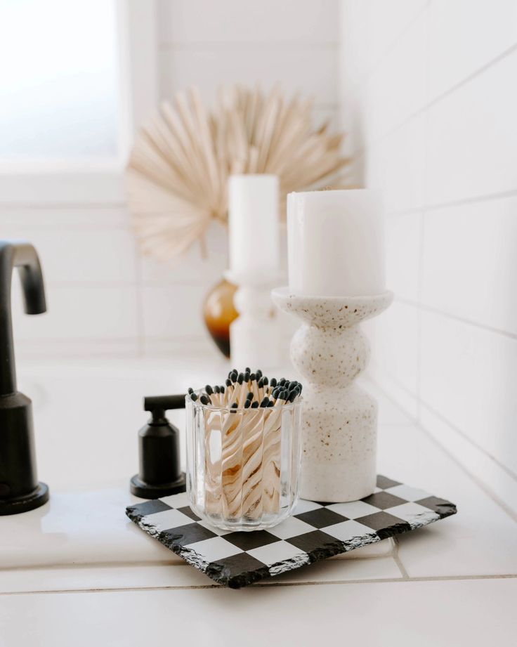 a bathroom sink with soap and toothbrushes on the counter top next to a black faucet