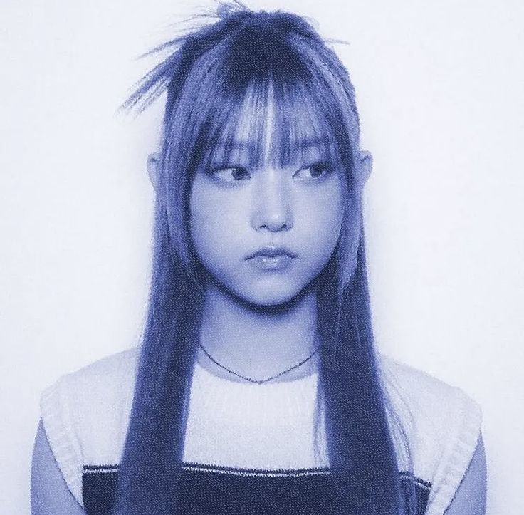 a woman with long hair and bangs standing in front of a white wall