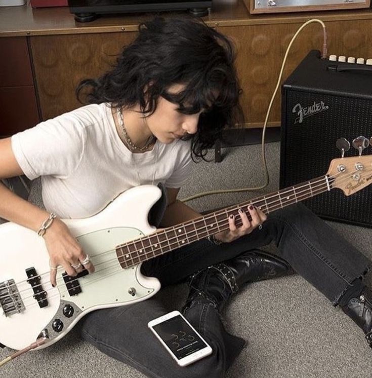 a young man sitting on the floor with his guitar and amp in front of him