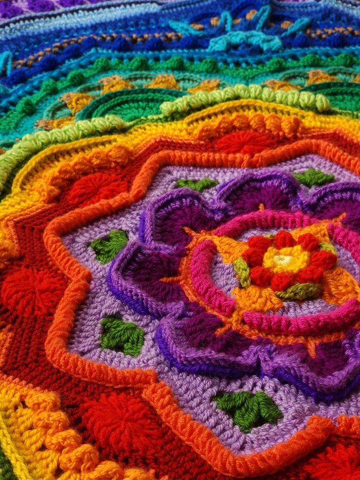 a multicolored crocheted blanket with a flower on it's center