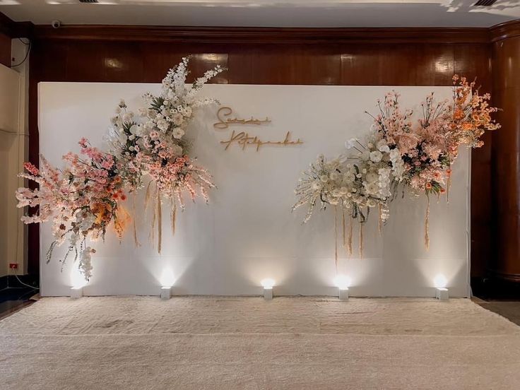 flowers are arranged on the wall in front of candles