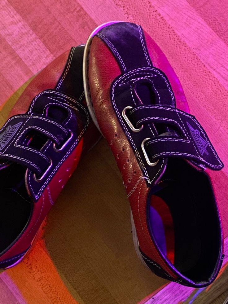 a pair of purple shoes sitting on top of a skateboard