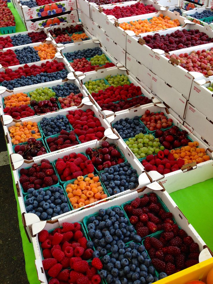 many boxes of berries and oranges are on display