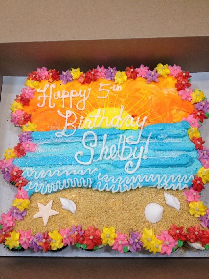 a birthday cake in a box decorated with flowers and sand