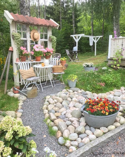 a garden area with flowers and chairs in the grass, next to a gazebo