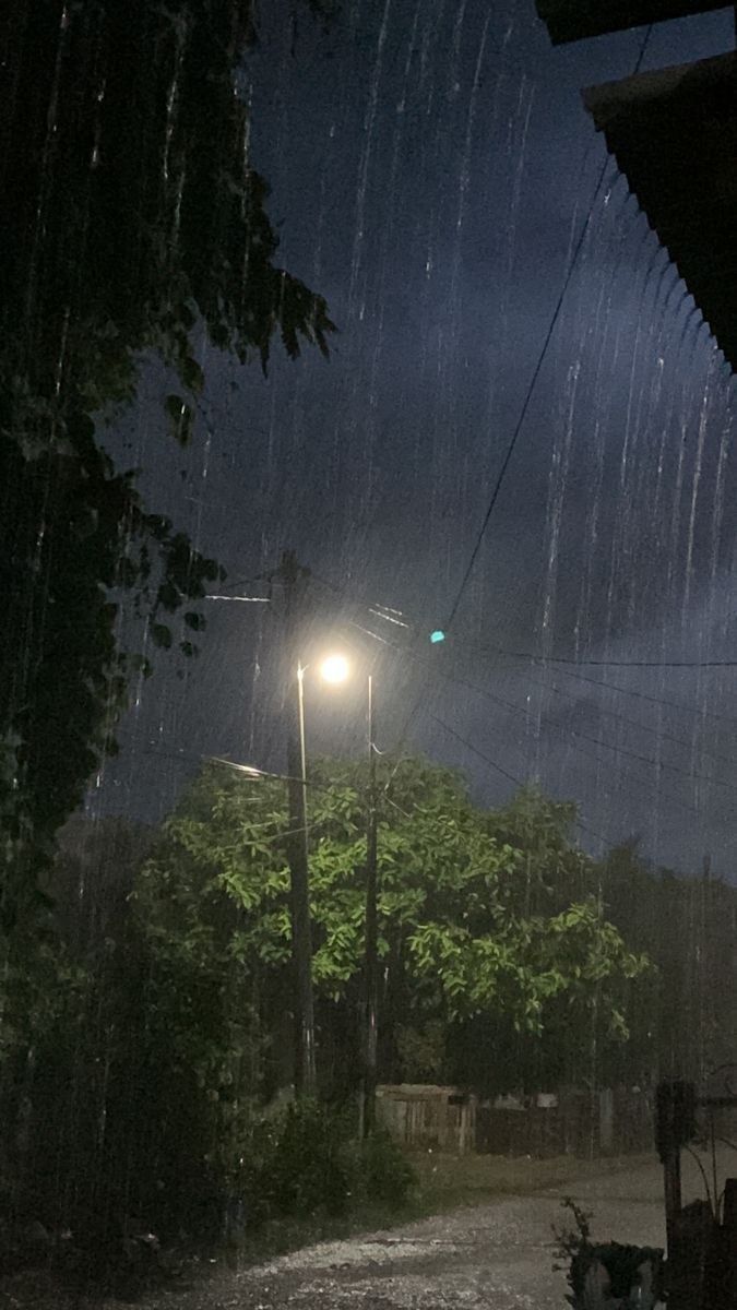 a street light sitting on the side of a road under a cloudy sky at night