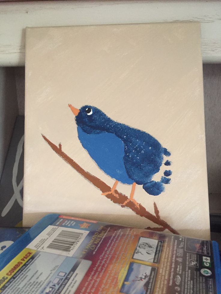 a blue bird sitting on top of a wooden branch next to a magazine and paper