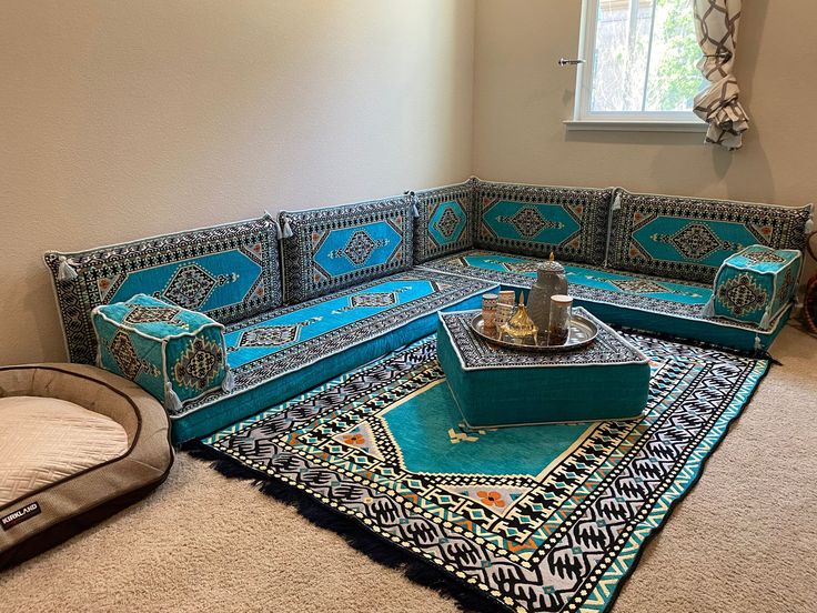 a living room with a blue couch and rugs on the floor in front of a window