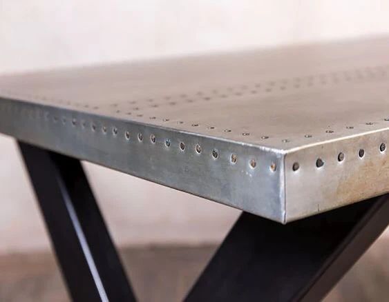 a metal table with holes in the middle and black legs on it's sides