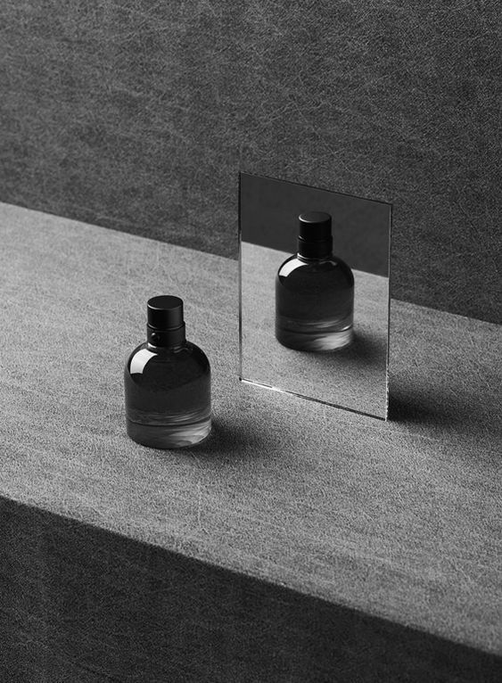 black and white photograph of two bottles in front of a mirror on top of a table