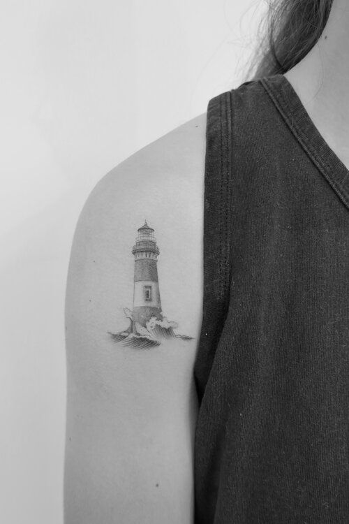 a black and white photo of a woman's arm with a lighthouse tattoo on it