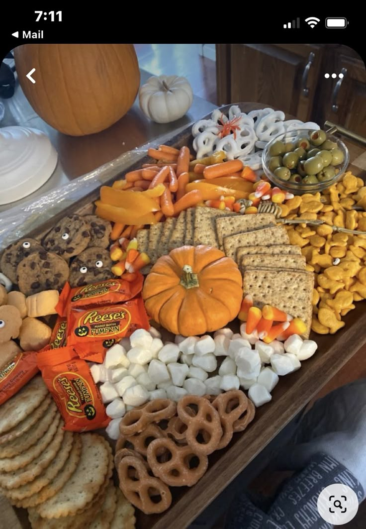 an assortment of snacks are displayed on a table with pumpkins and other food items