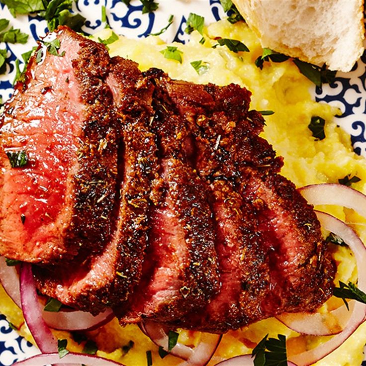 a plate with meat, onions and bread on it