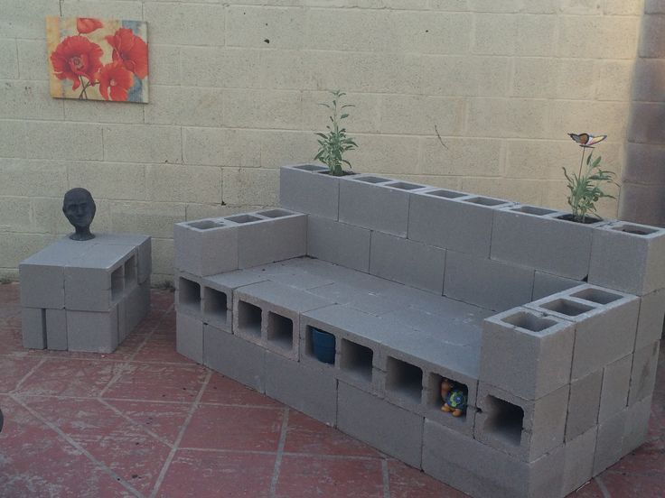 a cement bench and planter made out of cinder blocks on the ground next to a brick wall