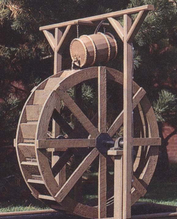 a wooden water wheel sitting in the grass