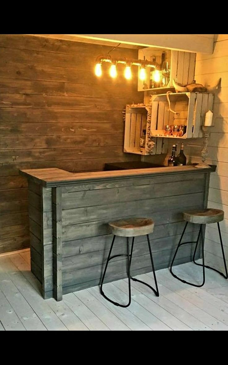 two stools sit at the bar in front of a wooden wall with lights on it