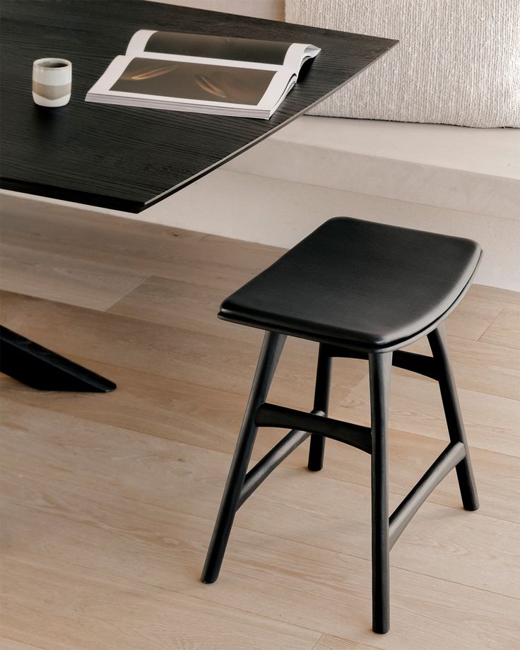 a black stool sitting next to a table with a laptop on it and a tablet