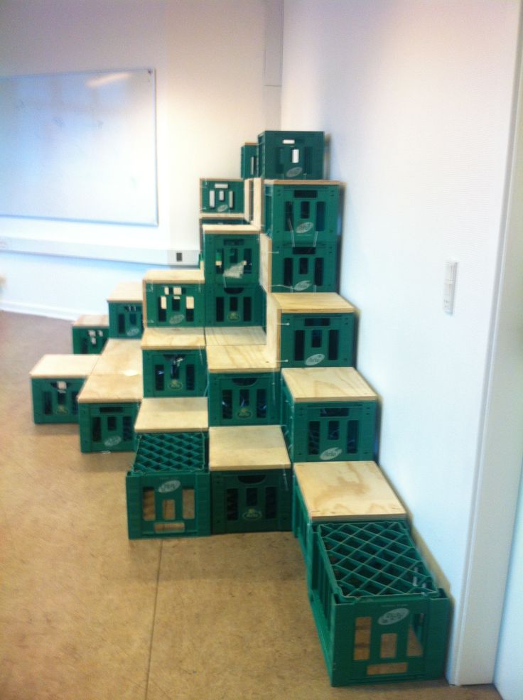 several green crates stacked on top of each other in front of a white wall and window