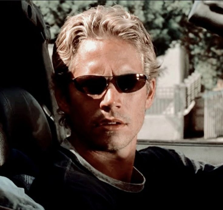 a man with sunglasses sitting in the back seat of a car and looking at something